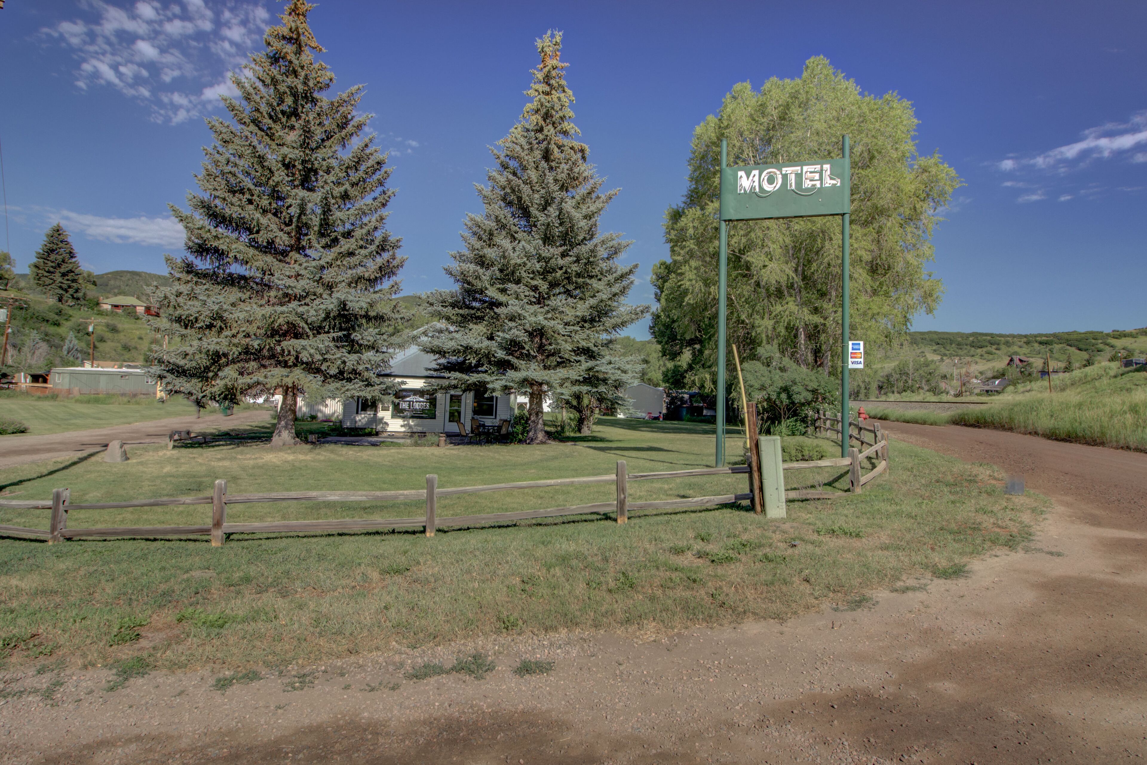 Un letrero de motel con la palabra 'Motel', rodeado de árboles y césped.
