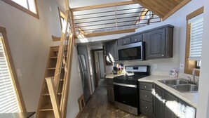 Een moderne keuken met houten vloer, een inbouwoven, magnetron en een roestvrijstalen spoelbak.
