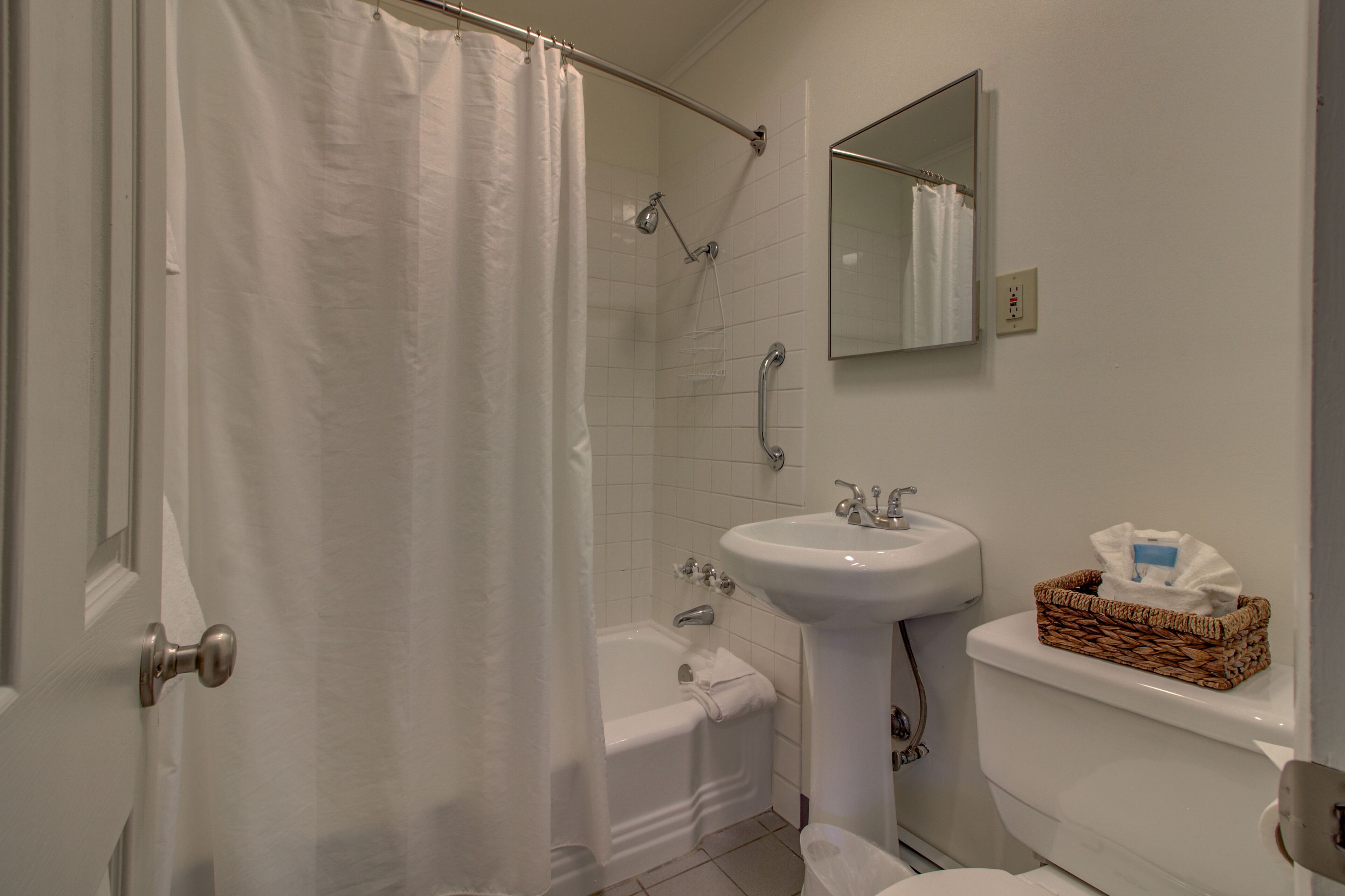 Un baño con cortina de ducha, bañera, lavamanos e inodoro.