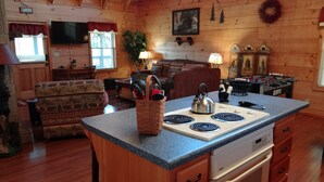 L’intérieur chaleureux d’un chalet comprend un coin cuisine équipé d’une cuisinière, une table à manger et un canapé.
