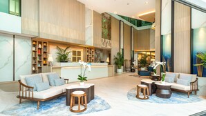 A spacious lobby with a reception desk, seating area, and a staircase leading to an upper level. - Hilton Garden Inn Phuket, Thailand (Choeng Thale)