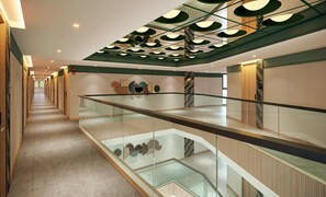 A modern interior with a glass railing, a tiled floor, and a ceiling with circular light fixtures. - Mamaka Phuket, Tapestry Collection by Hilton (Choeng Thale)