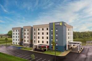 A multi-story hotel with a modern design, featuring a prominent 'HOME 2 HOME' sign, a covered outdoor seating area, and a parking lot. - Home2 Suites by Hilton Jackson/Pearl, MS (Pearl)