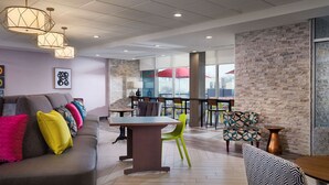 Un espacio lounge moderno con un sofá, sillas y una mesa de comedor.