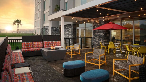 Un patio al aire libre con mobiliario, una chimenea y luces colgantes.