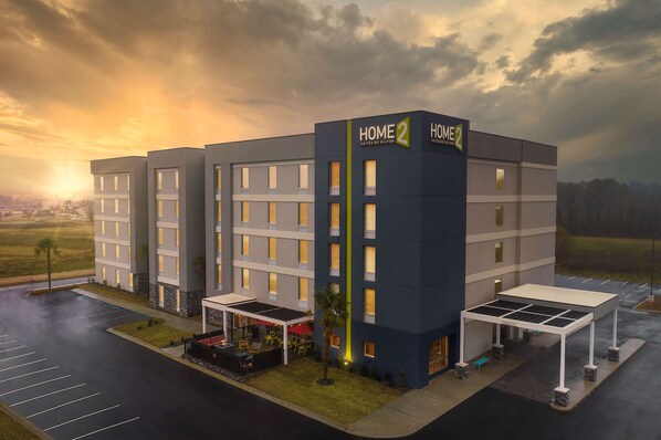 A modern hotel with a prominent "HOME 2" sign, multiple floors, and a covered outdoor seating area. - Home2 Suites by Hilton Jackson/Pearl, MS (Pearl)