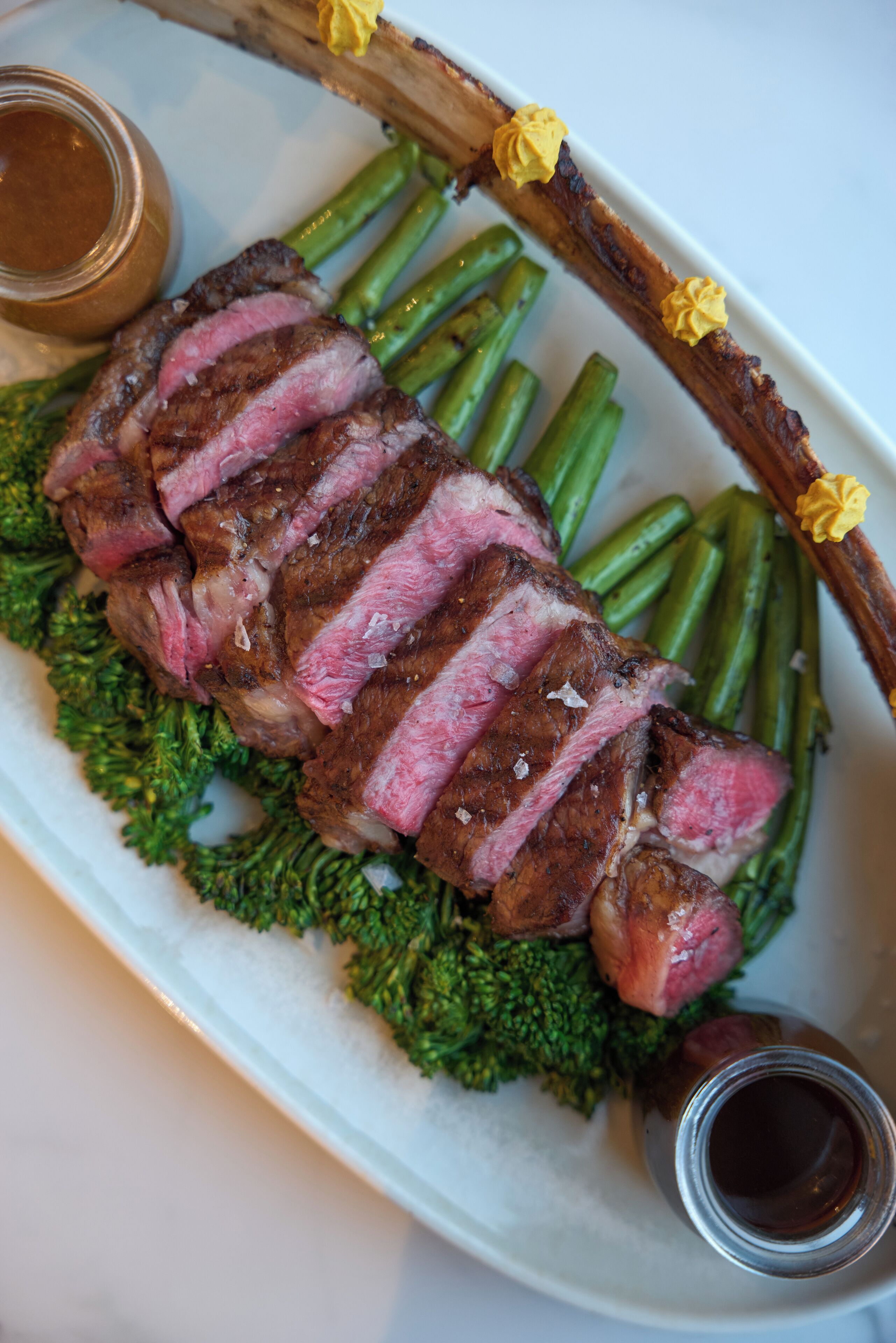A plate of steak with green beans and a sauce.