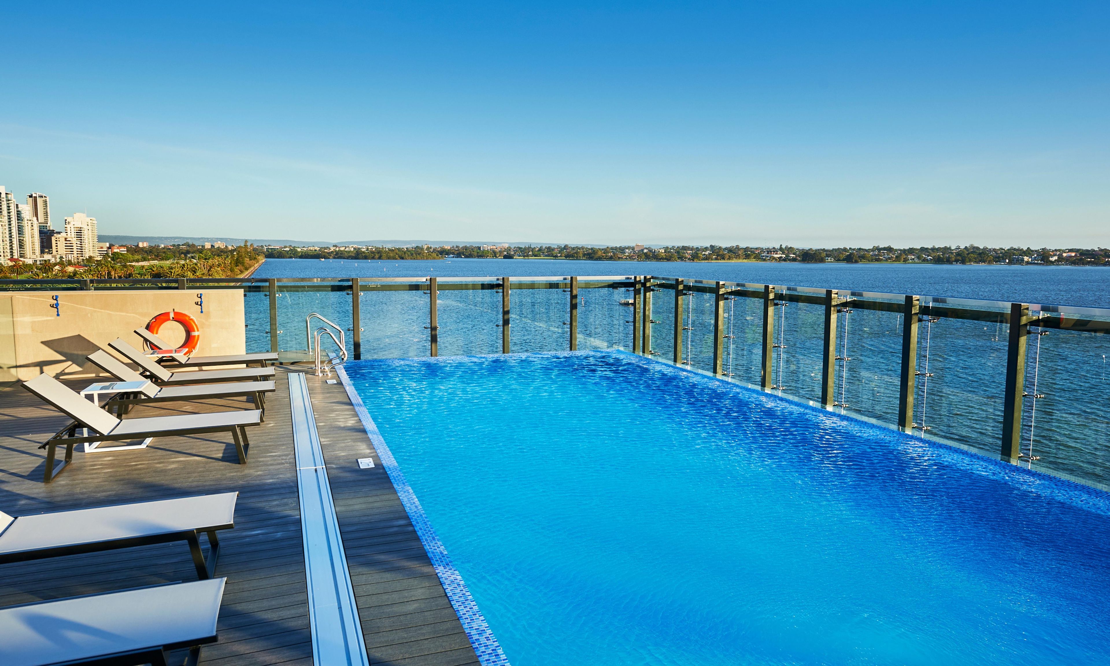 Una piscina con vista al agua, sillas de deck y un flotador.