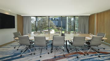 Un salón de conferencias con una gran mesa, seis sillas y una televisión en la pared.
