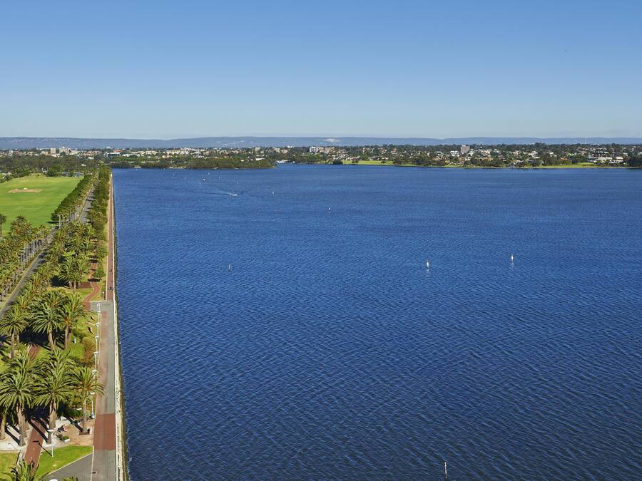 Una extensa masa de agua con un parque y edificios al fondo.