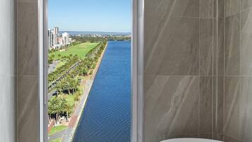 A bathroom with a bathtub, a window with a view of a river and cityscape.