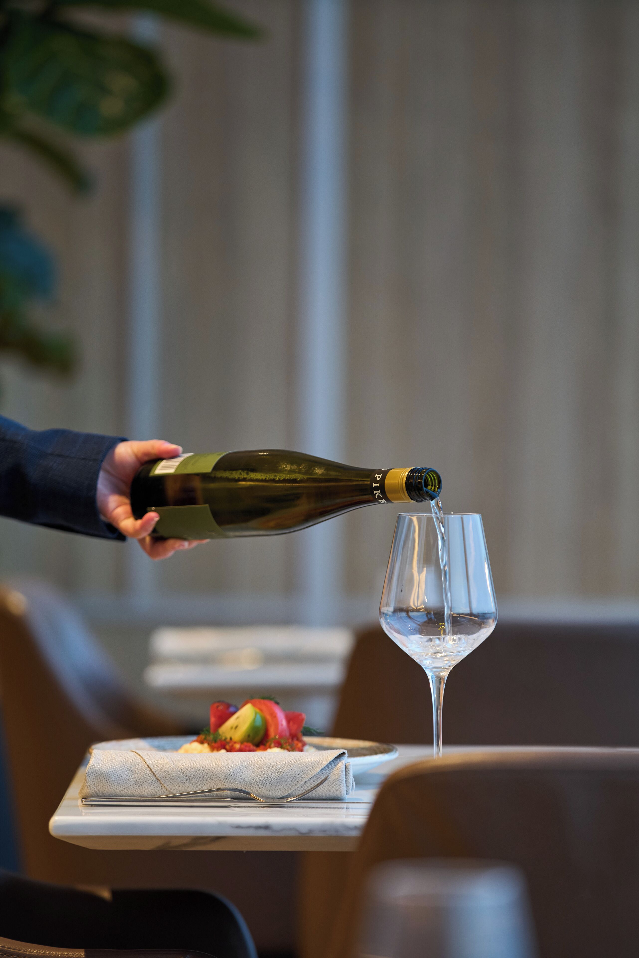 Eine Person gießt Champagner in ein Glas auf einem Tablett mit einem Dessert.