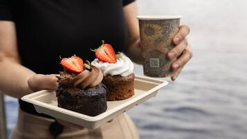 Una persona che tiene un vassoio con due cupcake e una tazza di caffè.