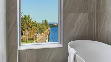 Un baño moderno con un ventanal grande, una bañera y vista al frente marítimo.