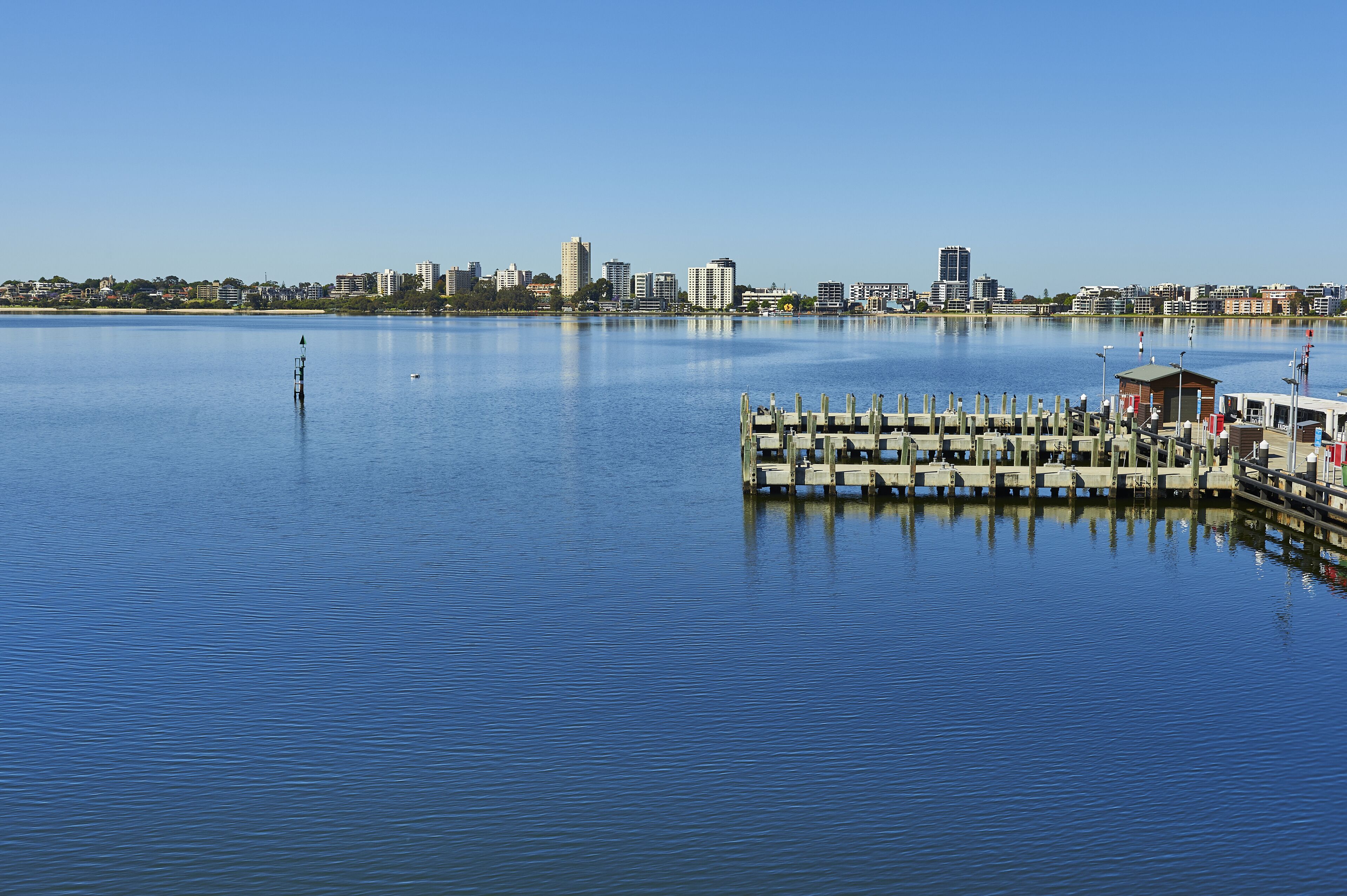 Vista al agua con un muelle y el horizonte de la ciudad al fondo.