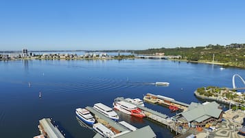 Uma marina com vários barcos atracados, uma ponte ao fundo e edifícios ao longo da orla.