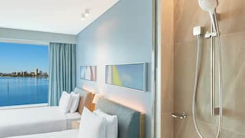 Habitación de hotel con una cama grande, ducha, vista a la ciudad y diseño moderno.