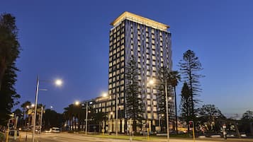 Um hotel moderno com design arquitetônico imponente, destacando-se por uma entrada de canto e vários andares.