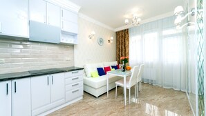 A modern kitchen with white cabinets, a black countertop, and a dining area with a white table and chairs. - Comfortable apartment in a new house (Kyiv)