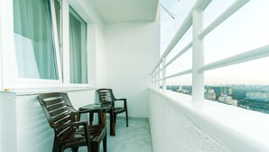 A balcony with two wooden chairs and a small table, overlooking a cityscape. - Comfortable apartment in a new house (Kyiv)