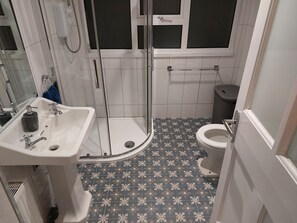 A bathroom with a shower, toilet, and sink.
