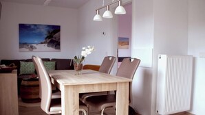 A dining area with a wooden table, chairs, and a vase of flowers. There is a painting on the wall and a radiator on the wall. - Holiday home De Wickinger with your own Steiger angler are welcome! (Wervershoof)