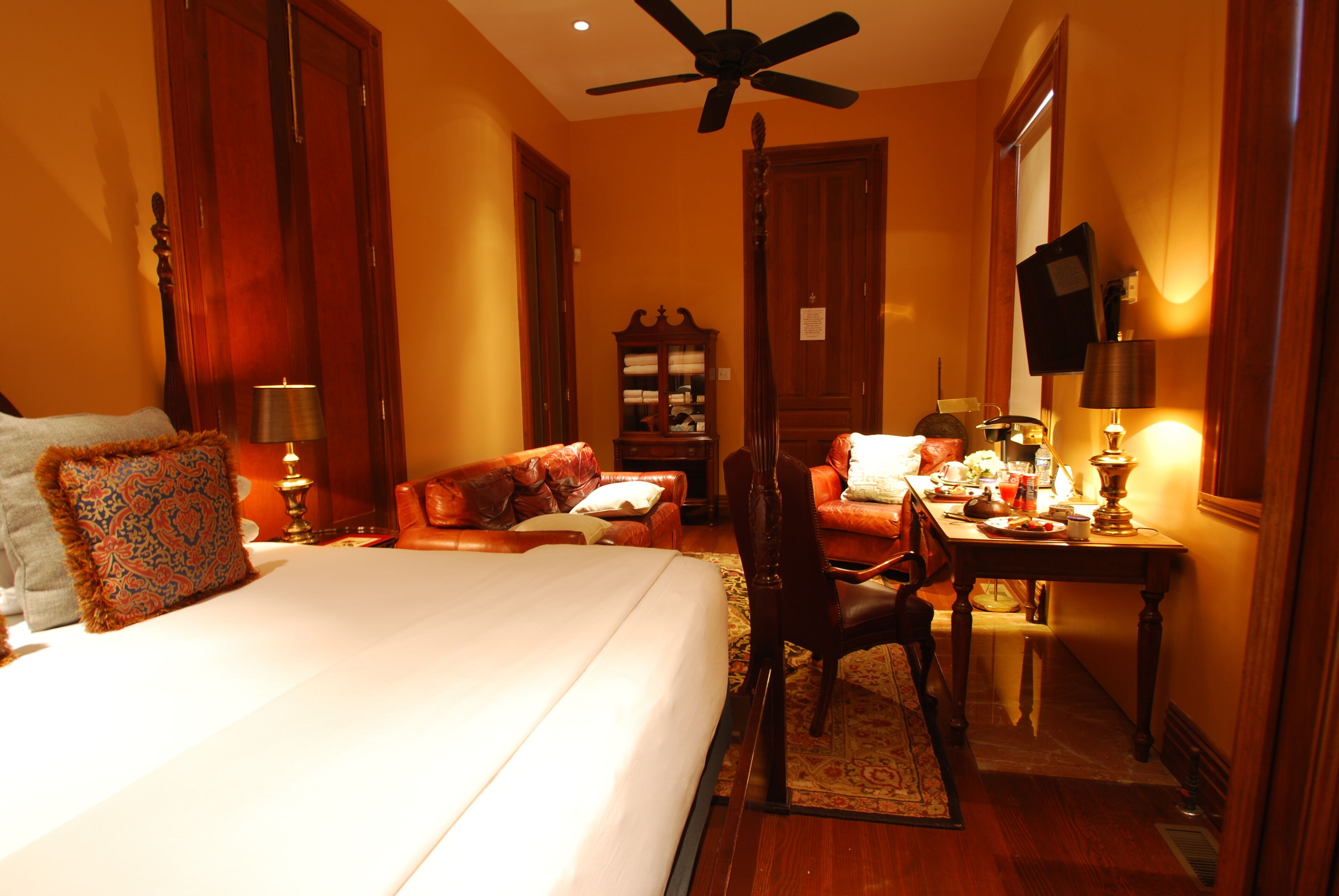A hotel room with a bed, a desk, a chair, a television, and a wardrobe.