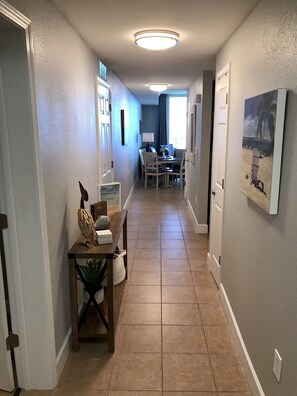 Un couloir qui se termine par un espace repas, comprenant une table et des chaises.