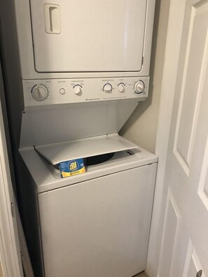A compact washer and dryer unit with a control panel and a box of All brand stain remover on top.
