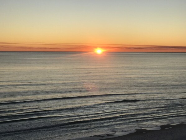 A sunset over a calm sea with gentle waves.