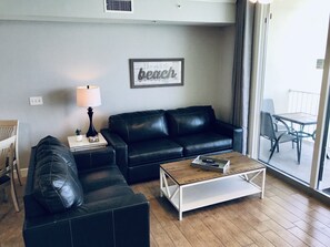 A living room with a black leather sofa, a wooden coffee table, and a framed wall decoration.