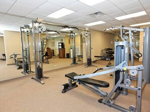A gym with various exercise machines and a large mirror wall.