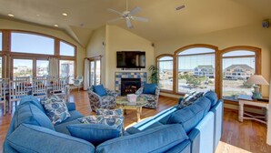 A spacious living room with a fireplace, large windows, and a ceiling fan. - Spectacular OCEAN and SOUND VIEW Private Pool (Salvo)