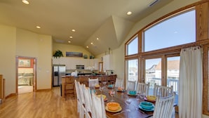 A spacious kitchen with wooden cabinets, a dining table set for six, and large windows offering a view of the neighborhood. - Spectacular OCEAN and SOUND VIEW Private Pool (Salvo)