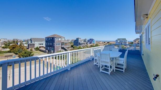 A balcony with a white railing, a table, and two chairs. - Spectacular OCEAN and SOUND VIEW Private Pool (Salvo)