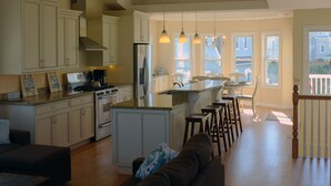 Cocina amplia con armarios blancos, una isla central e iluminación colgante.