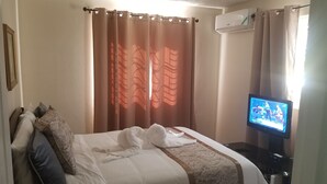 Een hotelkamer met een bed, een televisie en een airconditioner.