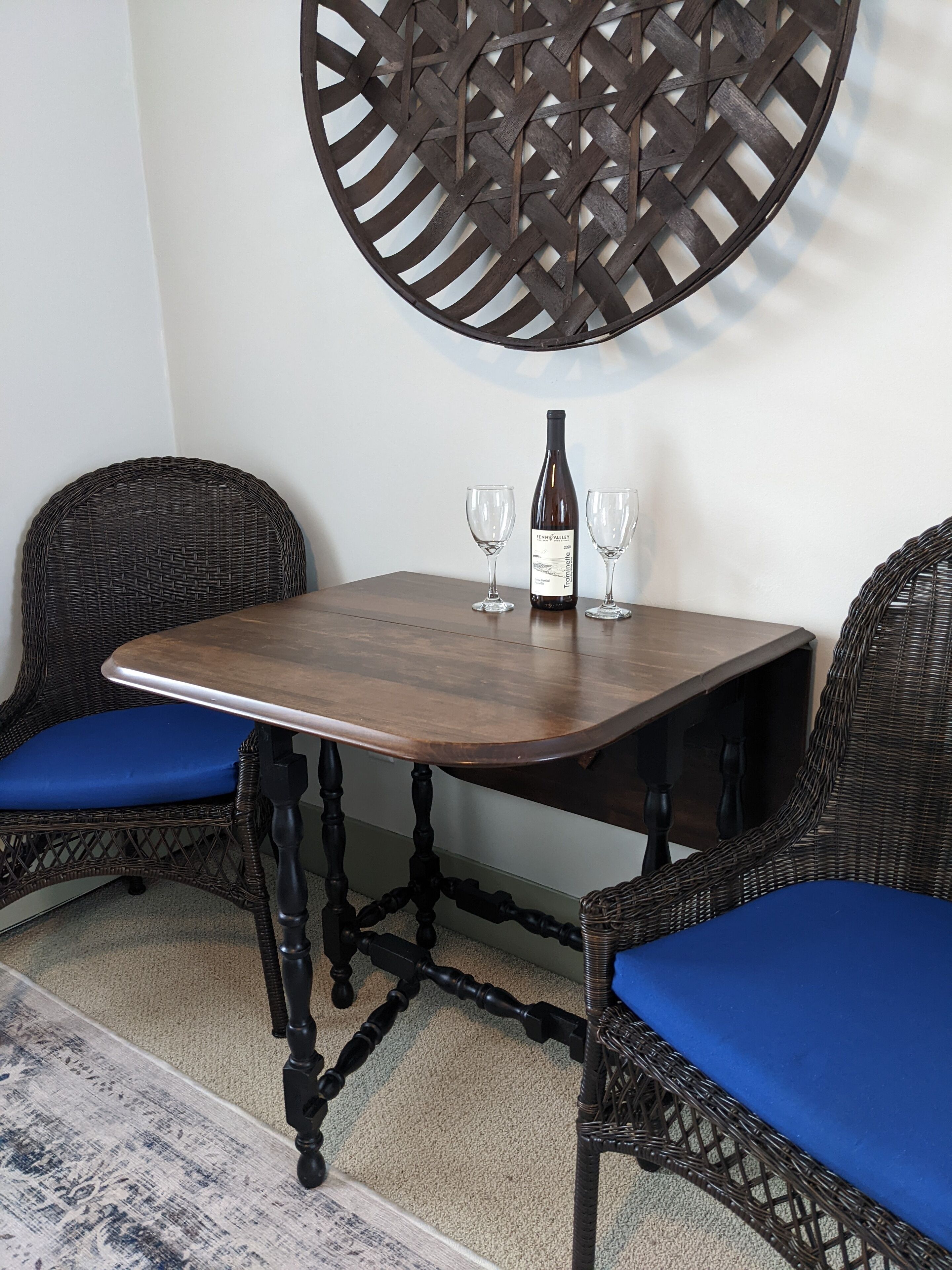 A dining table with two chairs, a bottle of wine, and two glasses.