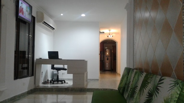 A clean, modern living room with a sofa, a small table, and a TV mounted on the wall. - Hotel Casa Garces Cartagena (Cartagena)