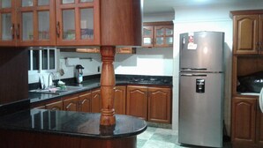 A kitchen with wooden cabinets, a stainless steel refrigerator, and a granite countertop. - Hotel Casa Garces Cartagena (Cartagena)