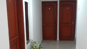 A hallway with three wooden doors numbered 3, 4, and 5. There is a potted plant on the floor. - Hotel Casa Garces Cartagena (Cartagena)