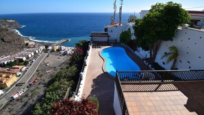 A rooftop pool with a view of the ocean, surrounded by buildings and greenery. - Villa Altos de Santiago (Alajeró)