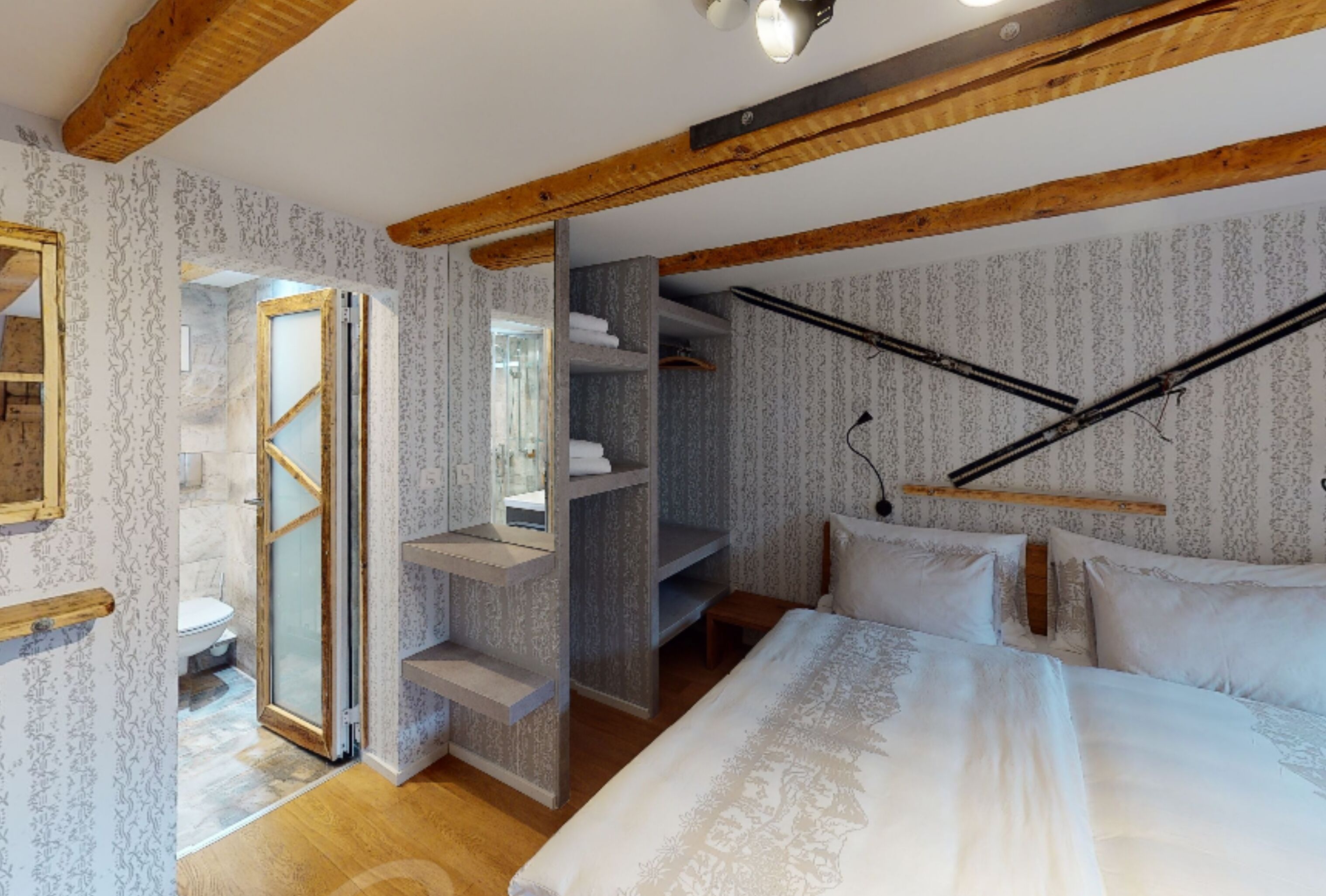 Un dormitorio con cama, vigas de madera, armario y baño con inodoro y ducha.