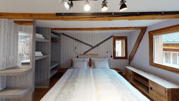 Un dormitorio con una cama grande, estanterías empotradas, un escritorio y una ventana con vistas.