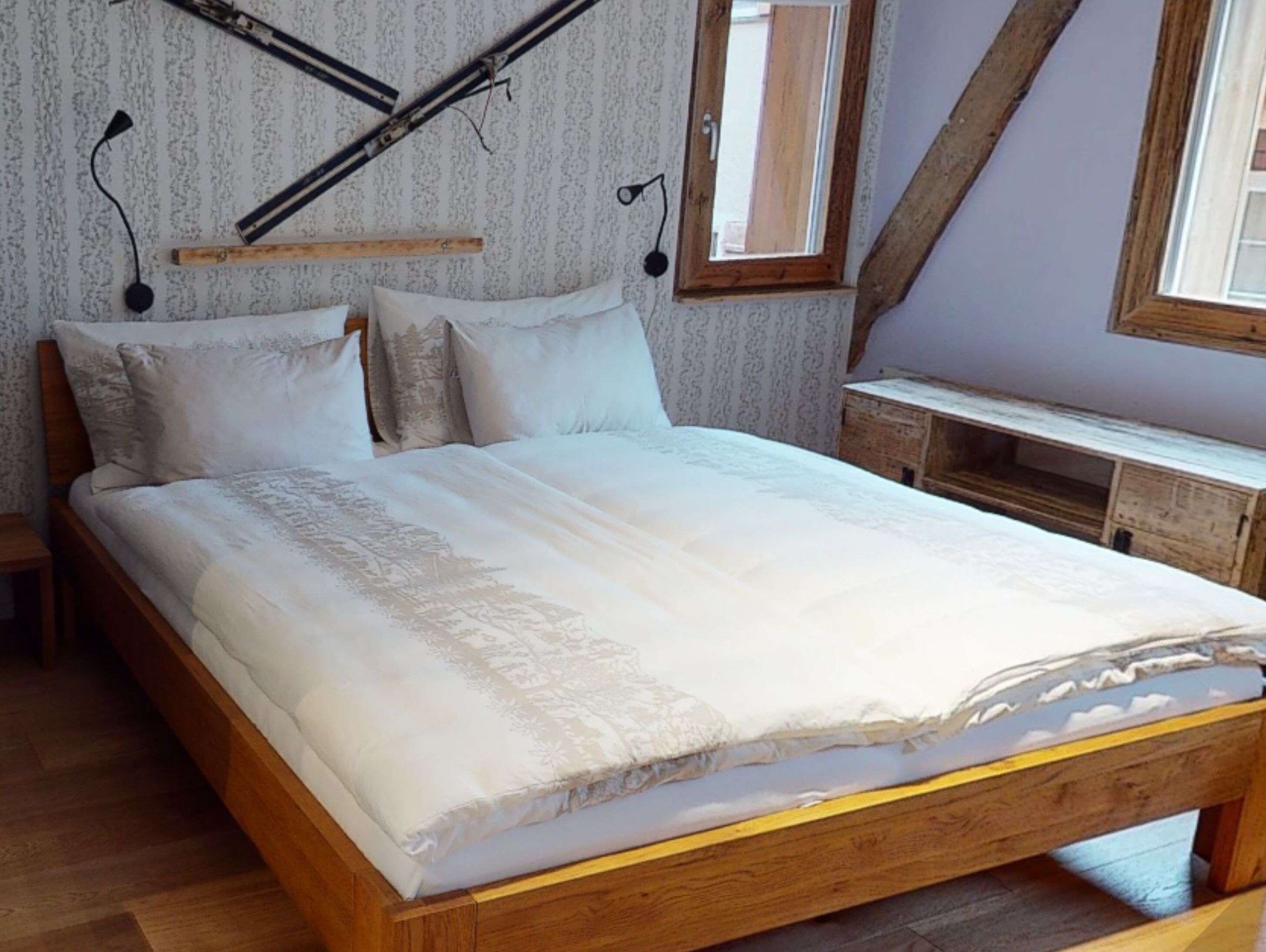 Un dormitorio con una cama de madera, una mesita de noche, un escritorio y una ventana con vistas.