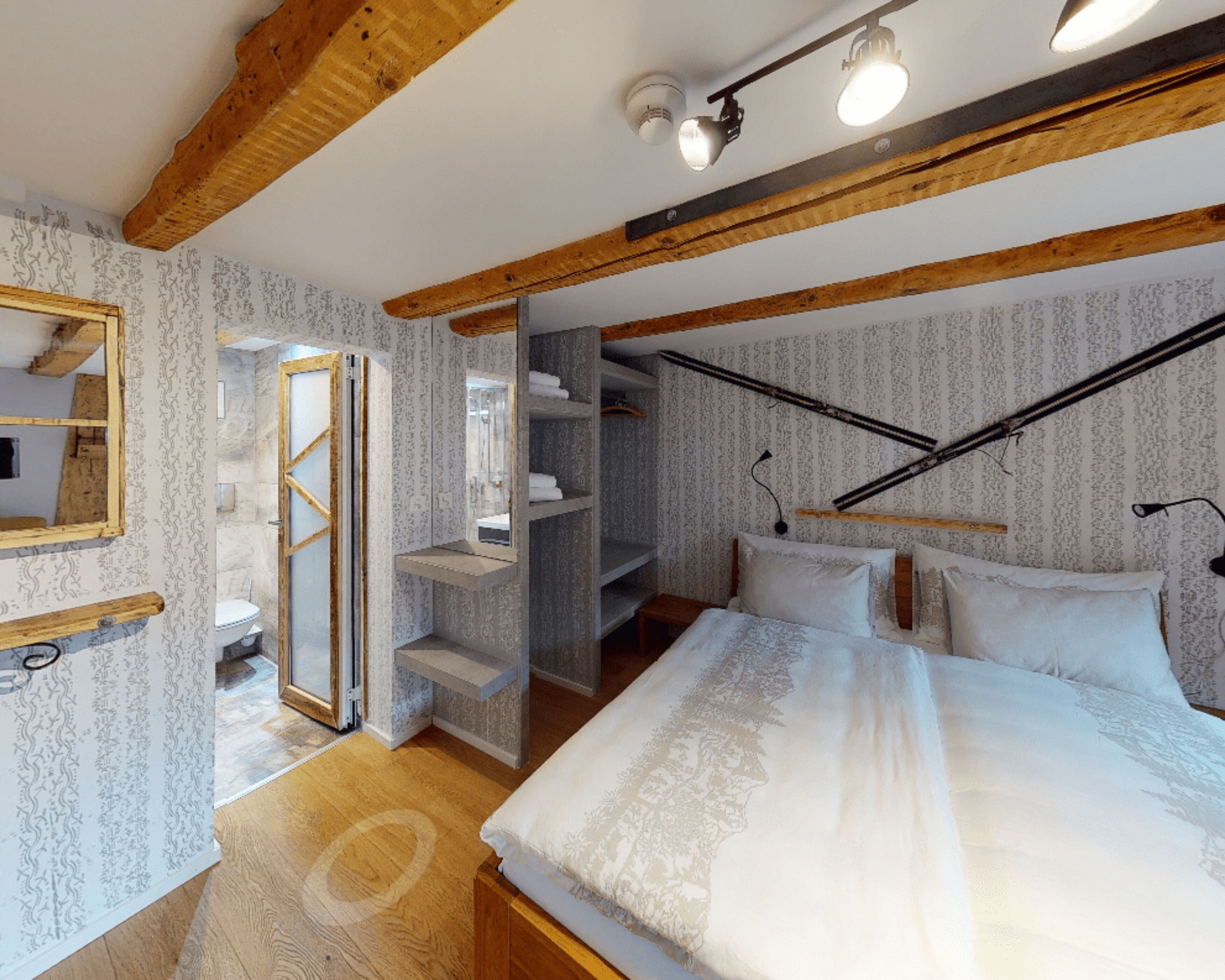 A bedroom with a wooden ceiling, a bed with white linens, a built-in wardrobe, and a mirror.