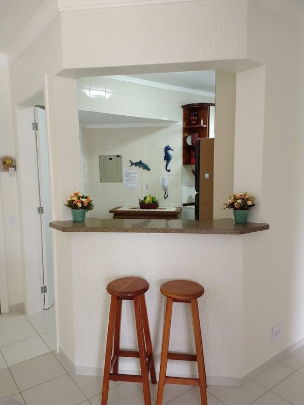 A kitchen area with a counter, two stools, and decorative items. - RIVIERA OF SAINT LOURCE. APARTMENT BETWEEN BEACH AND SHOPPING - MODULE 4. (São Lourenço)