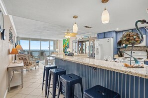 A kitchen with a bar area, a ceiling fan, and a view to the outside.