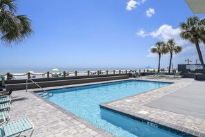 A swimming pool with a view of the beach, lounge chairs, and palm trees. - 0801 Waters Edge Resort 3 Bedroom Condo by RedAwning (Murrells Inlet)