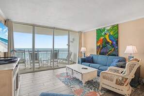 A room with a balcony, a sofa, a chair, a coffee table, and a painting. - 0801 Waters Edge Resort 3 Bedroom Condo by RedAwning (Murrells Inlet)